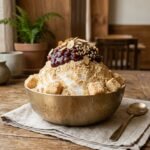 Traditional Korean Injeolmi Bingsu served in a brass bowl topped with sweet red bean tteok rice cakes and roasted soybean powder